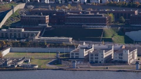 AX119_123.0000182F - Aerial stock photo of Riverfront buildings at Sing Sing Prison in Autumn, Ossining, New York