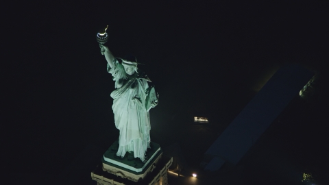 AX121_168.0000211F - Aerial stock photo of Statue of Liberty at nighttime in New York