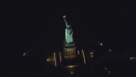 AX121_195.0000229F - Aerial stock photo of The side of the Statue of Liberty at night in New York