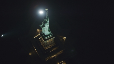 AX121_196.0000108F - Aerial stock photo of A bird's eye view of the back of the Statue of Liberty at night in New York