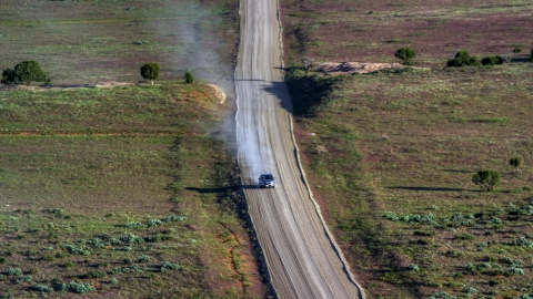 AX138_223.0000047 - Aerial stock photo of Silver SUV trailing a plume of dust on Hatch Point Road, Moab, Utah