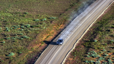 AX138_223.0000169 - Aerial stock photo of A silver SUV with a trail of dust on Hatch Point Road, Moab, Utah