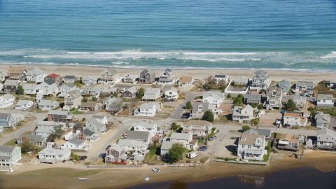 AX143_053.0000266 - Aerial stock photo of A group of oceanfront homes near ocean waves crashing, Humarock, Massachusetts