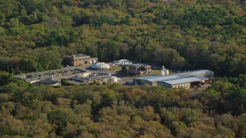 AX144_211.0000142 - Aerial stock photo of A water treatment plant surrounded by dense trees, Dartmouth, Massachusetts