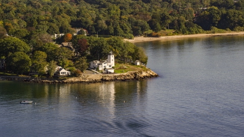 AX147_053.0000000 - Aerial stock photo of A lighthouse nestled among trees by cove, autumn, Beverly, Massachusetts