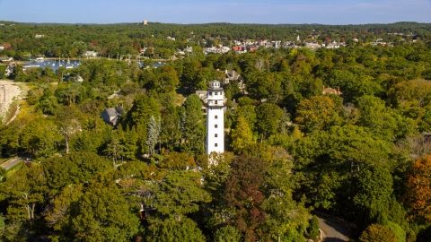 AX147_065.0000070 - Aerial stock photo of A light house and coastal community among trees, Manchester-by-the-Sea, Massachusetts