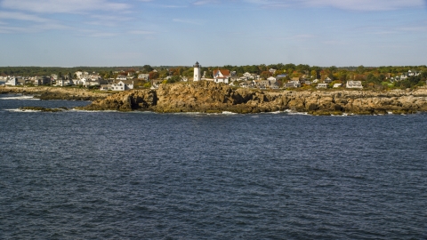 AX147_240.0000000 - Aerial stock photo of The Cape Neddick Light with the town behind it in autumn, York, Maine