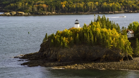 AX148_084.0000022 - Aerial stock photo of Owls Head Light beside the water and trees with fall foliage, autumn, Owls Head, Maine