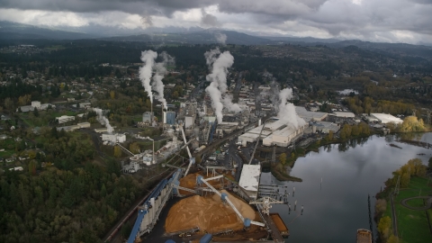 AX153_151.0000293F - Aerial stock photo of Steam rising from the Georgia Pacific Paper Mill in Camas, Washington