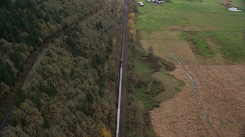 AX153_179.0000261F - Aerial stock photo of A train traveling past open fields in Washougal, Washington