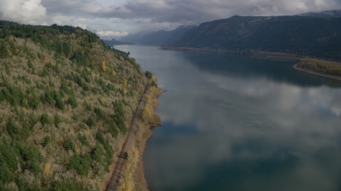 AX154_001.0000000F - Aerial stock photo of Train tracks at the bottom of a cliff in Columbia River Gorge, Oregon