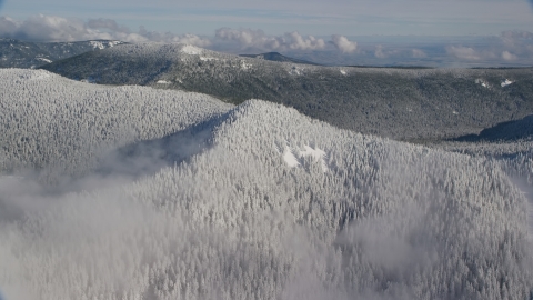 AX154_100.0000000F - Aerial stock photo of A snow covered mountain ridge and forest in the Cascade Range, Oregon