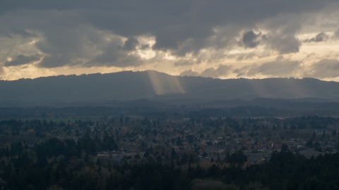 AX155_007.0000000F - Aerial stock photo of Cascade Range and godrays shining from clouds seen from suburban neighborhood, Beaverton, Oregon