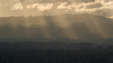 AX155_124.0000225F - Aerial stock photo of Godrays shining down on mountains near Beaverton, Oregon at sunset
