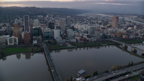 AX155_153.0000126F - Aerial stock photo of Downtown Portland skyscrapers and city park seen across the Willamette River at sunset