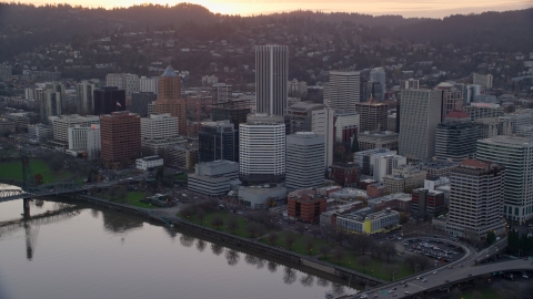 AX155_154.0000181F - Aerial stock photo of Downtown Portland skyscrapers and city park beside the Willamette River at sunset