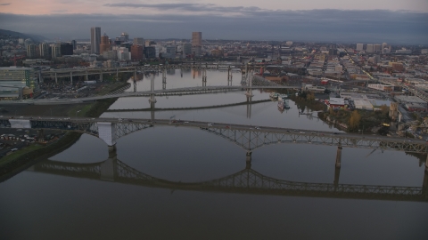 AX155_197.0000349F - Aerial stock photo of Ross Island Bridge and Willamette River bridges at sunset, reveal Downtown Portland, Oregon