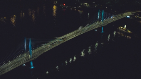 AX155_416.0000264F - Aerial stock photo of Tilikum Crossing bridge as a commuter train crosses the span at night in South Portland, Oregon