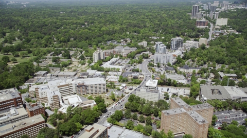 AX36_048.0000176F - Aerial stock photo of Peachtree Road near hospital, skyscrapers and wooded area in distance, Buckhead, Georgia