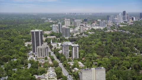 AX36_050.0000144F - Aerial stock photo of Peachtree Road past office buildings and wooded area, Atlanta, Georgia