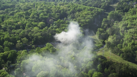 AX38_036.0000127F - Aerial stock photo of Smoke from a burning home in a wooded area, West Atlanta, Georgia
