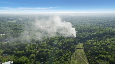 AX38_048.0000129F - Aerial stock photo of Smoke rising from a house fire in a wooded area, West Atlanta, Georgia