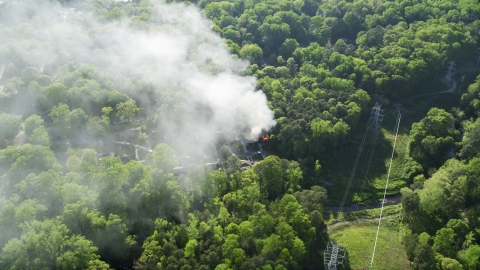 AX38_049.0000254F - Aerial stock photo of Smoke rising from a burning house in a wooded area, West Atlanta, Georgia