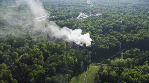 AX38_054.0000181F - Aerial stock photo of Smoke rising from a burning house in a wooded area, West Atlanta, Georgia