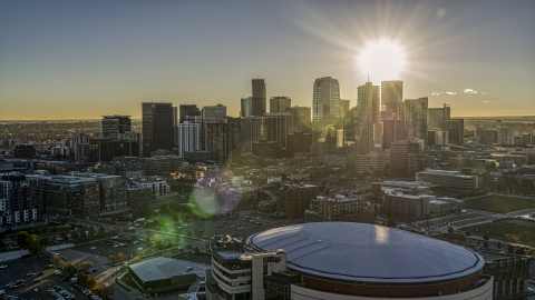 DXP001_000107 - Aerial stock photo of The sun shining above the skyscrapers of the city's skyline at sunrise, seen from arena in Downtown Denver, Colorado