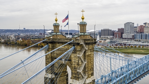 DXP001_000473 - Aerial stock photo of Flag on top of the Roebling Bridge spanning the Ohio River, Downtown Cincinnati, Ohio