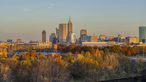 DXP001_092_0010 - Aerial stock photo of The city's skyline at sunset, seen from trees, Downtown Indianapolis, Indiana