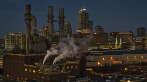 DXP001_093_0003 - Aerial stock photo of Factory smoke stacks with view of the city skyline at twilight, Downtown Indianapolis, Indiana