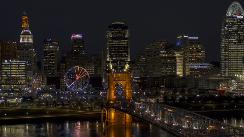 DXP001_098_0023 - Aerial stock photo of The Ferris wheel by Roebling Bridge at night, with city skyline in background, Downtown Cincinnati, Ohio