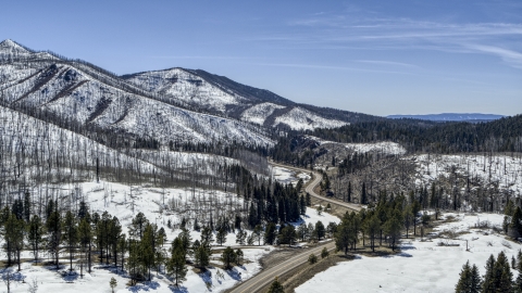 DXP002_134_0014 - Aerial stock photo of A winding road by snowy mountains, New Mexico