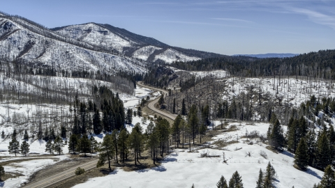 DXP002_134_0016 - Aerial stock photo of Winding road by snowy mountains and trees, New Mexico
