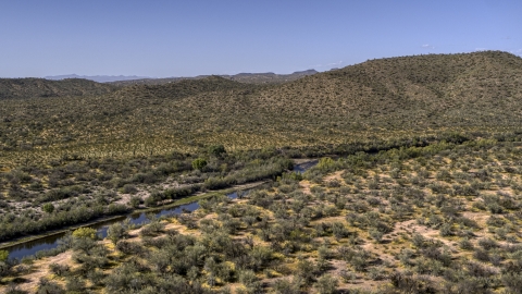DXP002_141_0022 - Aerial stock photo of A narrow river through the desert near a hill