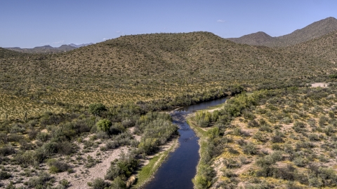 DXP002_141_0023 - Aerial stock photo of A narrow river bordered by desert hills with cactus