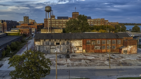 DXP002_197_0003 - Aerial stock photo of Abandoned factory building and water tower at sunset, Detroit, Michigan