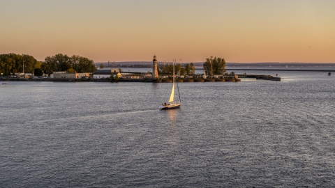 DXP002_204_0008 - Aerial stock photo of A sailboat on Lake Erie near a lighthouse at sunset, Buffalo, New York