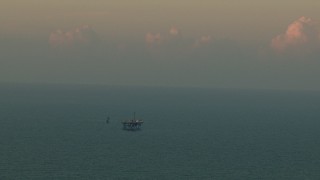 AF0001_000344 - HD aerial stock footage of an oil rig surrounded by open sea at sunrise, Gulf of Mexico