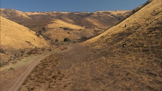 AF0001_000389 - HD stock footage aerial video of following a dirt road into the hills in Agua Dulce, California