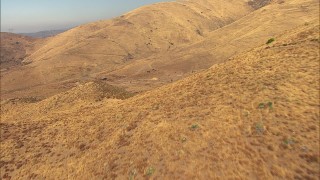 AF0001_000390 - HD stock footage aerial video flyby dry hills and reveal buildings in a valley in Agua Dulce, California