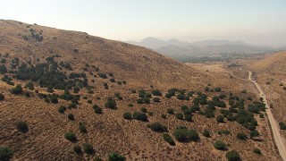 AF0001_000391 - HD aerial stock footage fly over dirt road and dry hillside to reveal rural homes in Agua Dulce, California