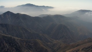 AF0001_000402 - HD stock footage aerial video fly over a mountain ridge to approach more mountains and a layer of clouds, Angeles National Forest, California
