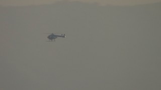 AF0001_000517 - HD aerial stock footage track a helicopter before it disappears behind a mountain, Tujunga, California, sunset