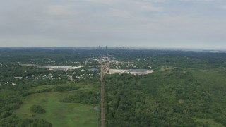 AF0001_000697 - HD aerial stock footage follow train tracks toward homes and warehouse by Sprague Pond, Downtown Boston in background, Readville, Massachusetts