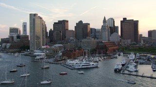 AF0001_000792 - HD aerial stock footage flyby boats at a downtown marina and riverfront skyscrapers in Downtown Boston, Massachusetts, sunset