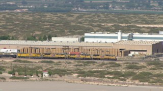 AF0001_000920 - HD stock footage aerial video of a train cruising past warehouse buildings in El Paso, Texas