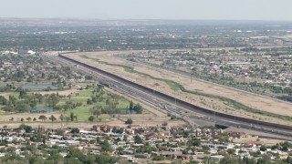 AF0001_000942 - HD aerial stock footage of the US/Mexico border fence by 375 freeway and golf course, El Paso, Texas