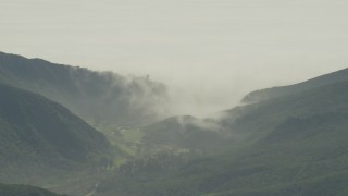 AF0001_000974 - 5K aerial stock footage of fog rolling over green mountains and reveal suburban homes in Los Angeles, California